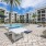 Three-Bedroom Luxury Apartments In Naples, FL - The Pearl Founders Square Apartments - Resort-Style Pool With with Sun Shelf, Cabanas, Plenty Of Seating Areas, Cornhole, And Ping Pong Table
