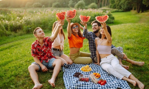 July Blog group eating outdoor and holding watermelon